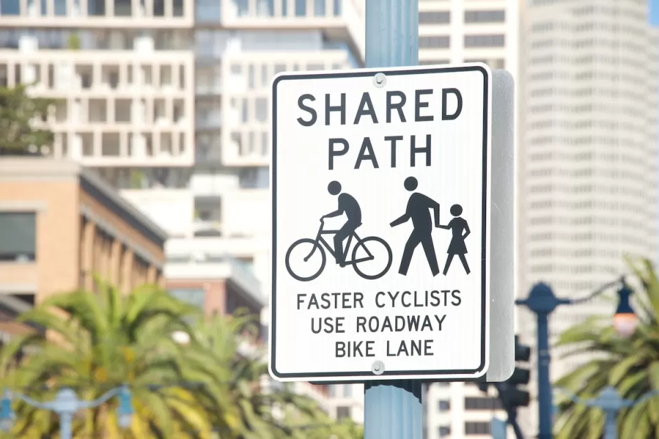 Close-up of "Shared Use Path" sign for pedestrians and cyclists on post in urban setting.